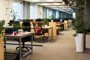 Employés travaillant dans un bureau frais et confortable avec des ventilateurs de bureau, des plantes d'intérieur et une zone de repos pendant une journée chaude